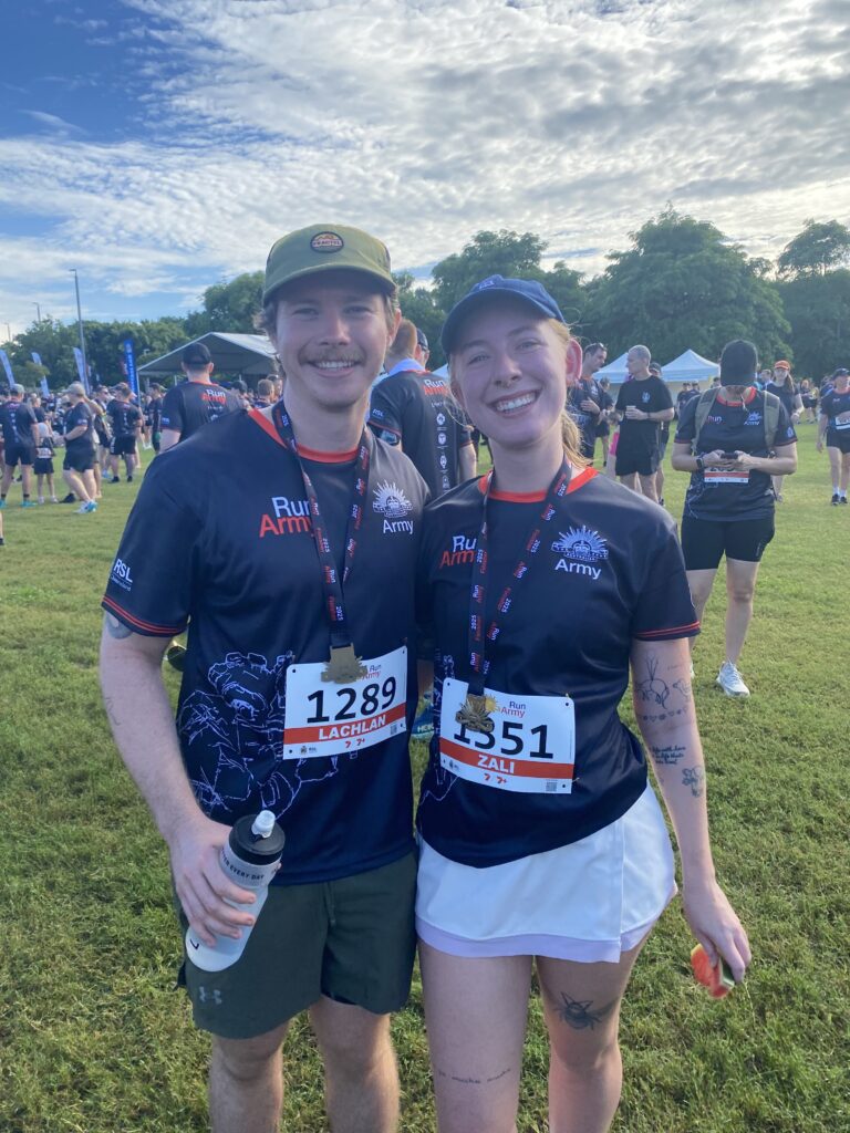 Two people, a man and a woman, in Army tshirts wearing run medals and run labels.