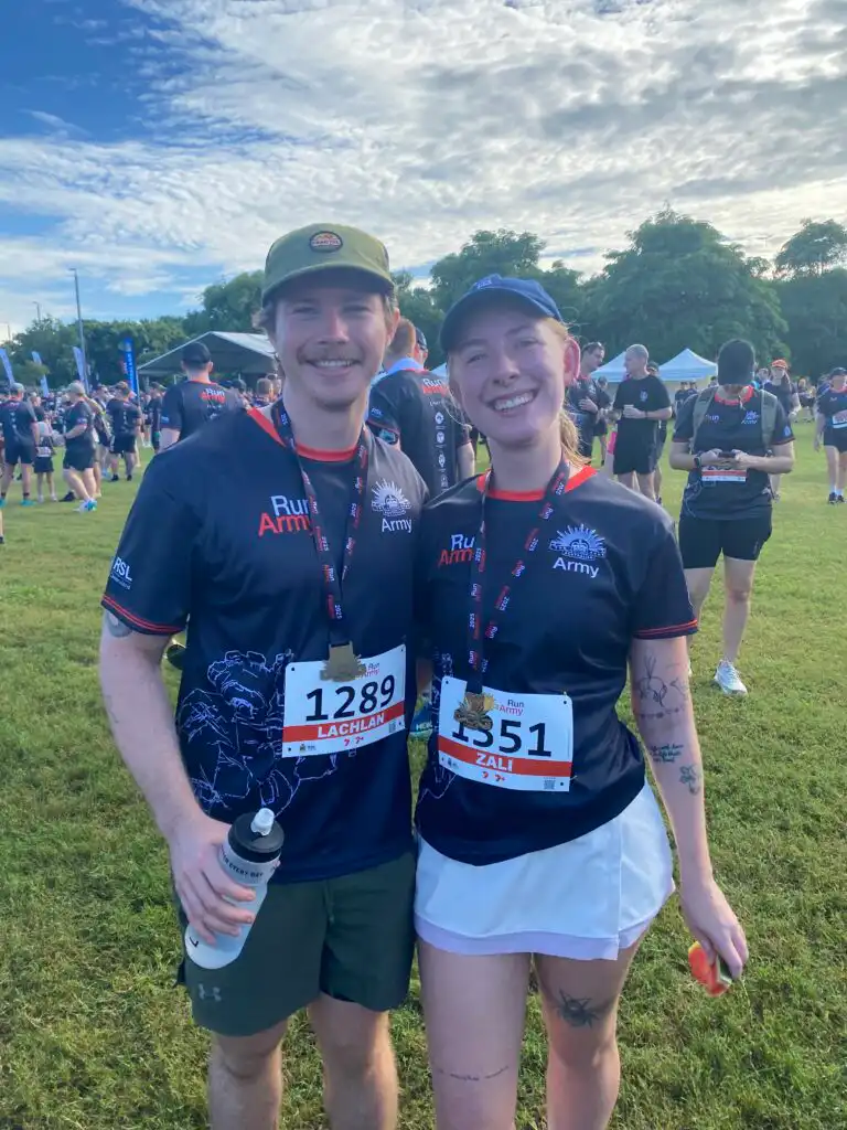 Two people, a man and a woman, in Army tshirts wearing run medals and run labels. 
